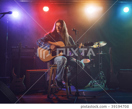 The musician plays an acoustic guitar. Scene 39194708