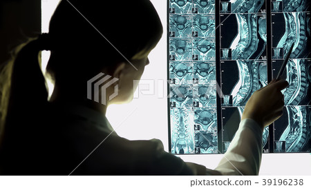 Surgeon looking at patient neck x-ray, pointing 39196238