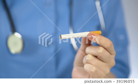 Woman doctor holding cigarette in hand, harmful Woman doctor holding cigarette in hand, harmful 39196855