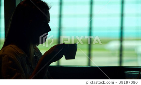 Young lady sitting at airport restaurant and Young lady sitting at airport restaurant and 39197080