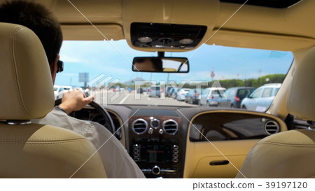 Busy rich male driving car in resort city Busy rich male driving car in resort city 39197120