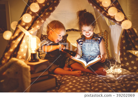 children boy and girl reading book with flashlight in tent children boy and girl reading book with flashlight in tent 39202069