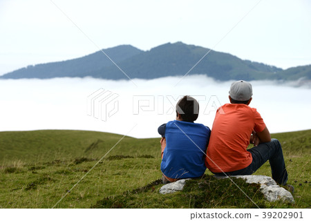 Children contemplating the mountain sitting on a Children contemplating the mountain sitting on a 39202901