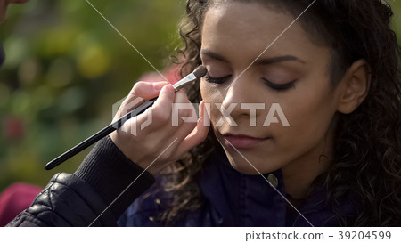 Makeup artist applying eyeshadow on eyes of model 39204599