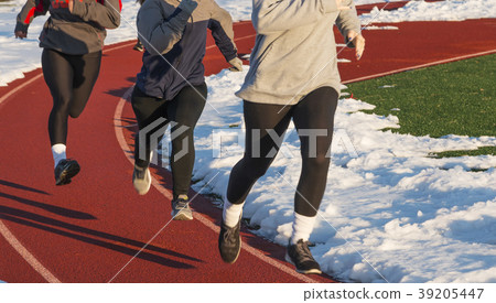 Three girls running on track at practice in snow Three girls running on track at practice in snow 39205447