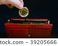 person's hand puts a gold bitcoin in a red wallet 39205666