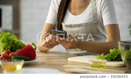 Woman choosing salad recipe on smartphone at the Woman choosing salad recipe on smartphone at the 39206455