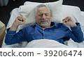 Pensioner stretching in his bed after awakening in 39206474