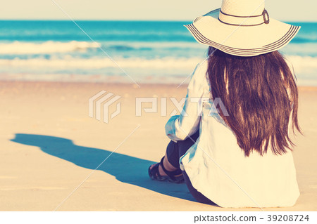 Woman in a hat sitting on the beach Woman in a hat sitting on the beach 39208724