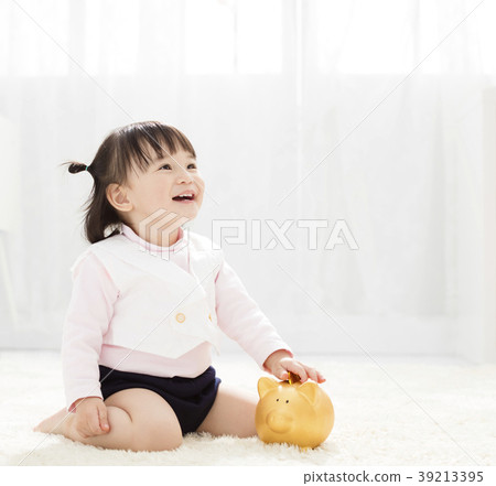 baby girl inserting a coin into piggybank 39213395