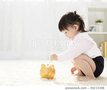 baby girl inserting a coin into piggybank baby girl inserting a coin into piggybank 39213396