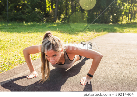 Fit woman doing push-ups at the park. 39214404