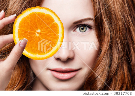 Young redhead woman with orange fruit slices. 39217708