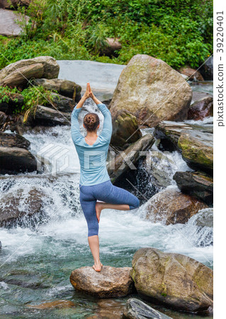 Woman in yoga asana Vrikshasana tree pose at Woman in yoga asana Vrikshasana tree pose at 39220401