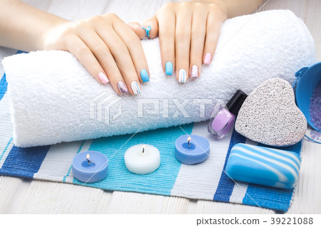 beautiful colored manicure with candle and towel on the white wooden table. 39221088