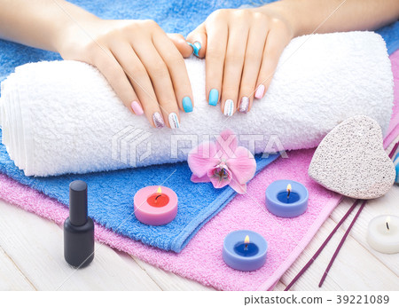 beautiful colored manicure with orchid, candle and towel on the white wooden table. beautiful colored manicure with orchid, candle and towel on the white wooden table. 39221089