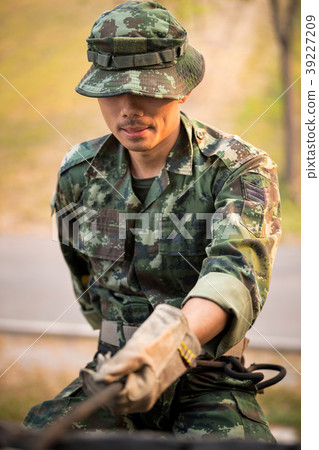 Military man does hanging on climbing equipment. 39227209