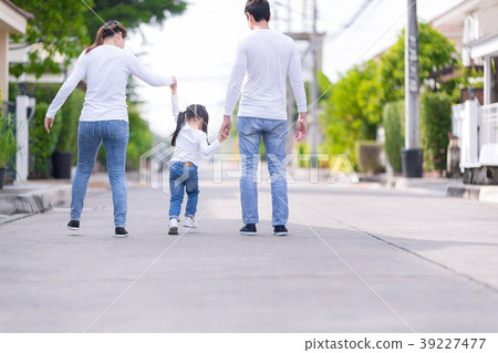 Parents and daughter are holding hands.  39227477