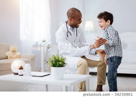Jovial male doctor making boy laugh Jovial male doctor making boy laugh 39230901