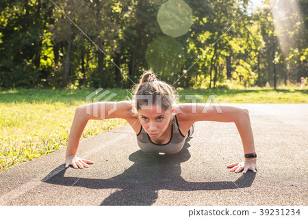 Fit woman doing push-ups at the park. 39231234