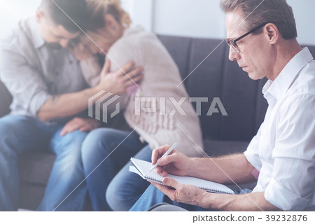Serious male psychologist working with a married Serious male psychologist working with a married 39232876