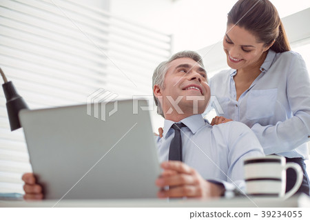 Cheerful positive woman standing behind her boss Cheerful positive woman standing behind her boss 39234055