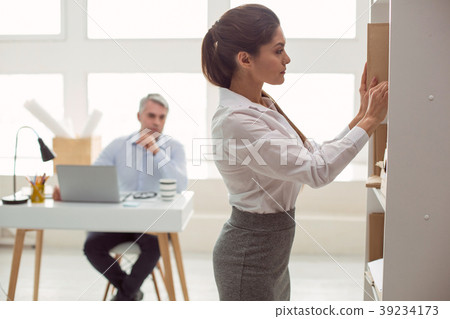 Smart young woman putting the books on the shelf Smart young woman putting the books on the shelf 39234173
