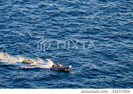 Man on rubber motor boat is towing the ski jet. 39247884