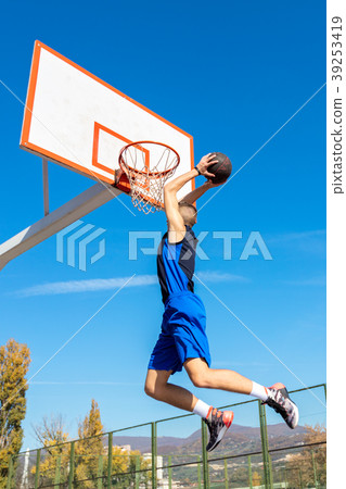 Young Basketball street player making slam dunk Young Basketball street player making slam dunk 39253419