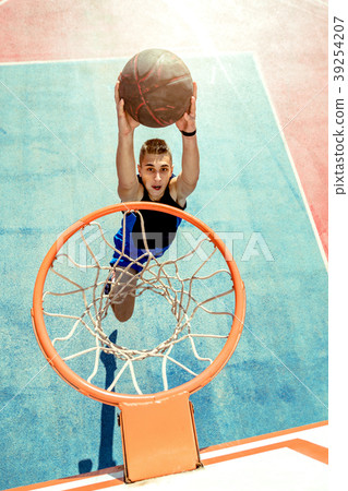 Young man jumping and making a fantastic slam dunk 39254207