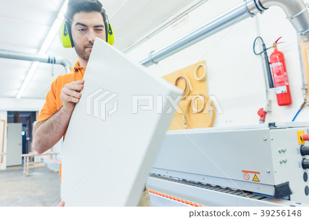 Carpenter in furniture factory working on veneer 39256148