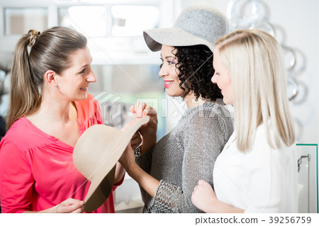 Girlfriends on shopping spree trying ladies hats 39256759