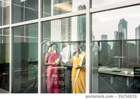 Indian employees sticking reminders on glass wall 39256839