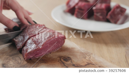 female hands slicing raw beef fillet for steak on 39257606
