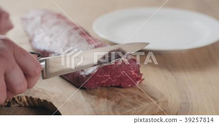 female hands slicing raw beef fillet for steak on 39257814