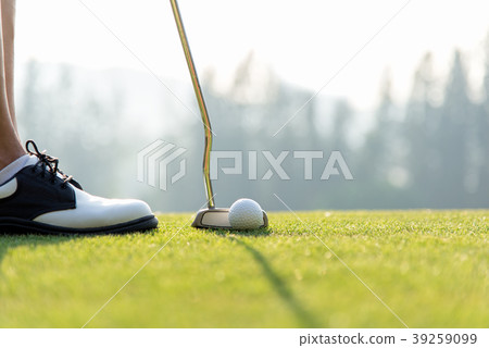 Golf player women at the putting green hitting bal 39259099