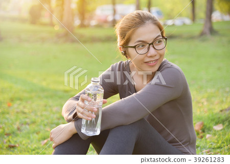 Asian female is resting and drinking water. Asian female is resting and drinking water. 39261283