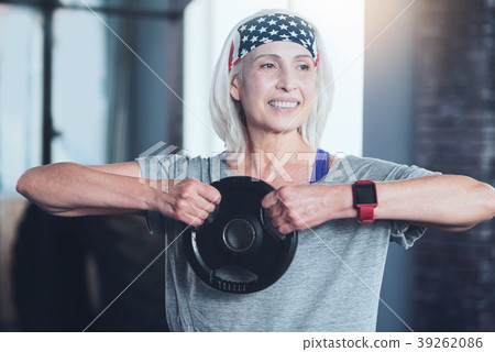 Beaming senior lady lifting kettle bell in gym Beaming senior lady lifting kettle bell in gym 39262086