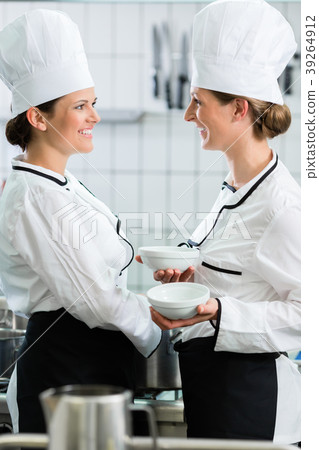 female chefs in commercial kitchen wearing white 39264912