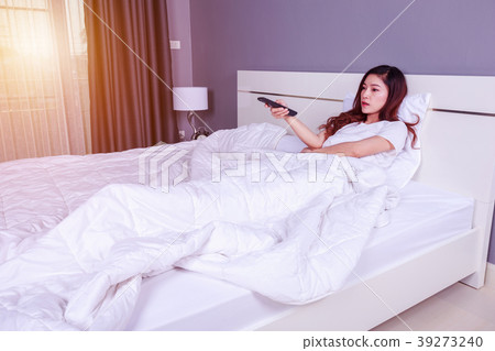 woman lying on a bed with remote control  39273240