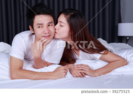 woman is kissing her husband in cheek on bed 39275525