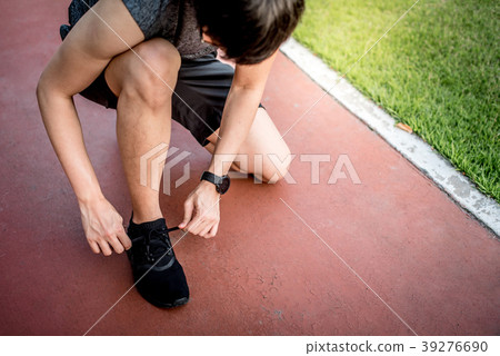 Asian man runner tying shoe laces on running track 39276690
