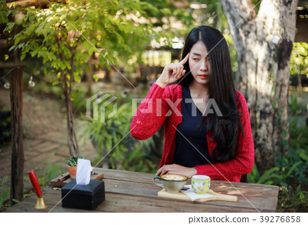 woman thinking and sitting on table with coffee in the garden woman thinking and sitting on table with coffee in the garden 39276858