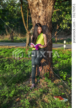 woman stading at the tree and reading a book in the park 39276951