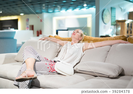 Woman shopping for new sofa in furniture store. 39284378