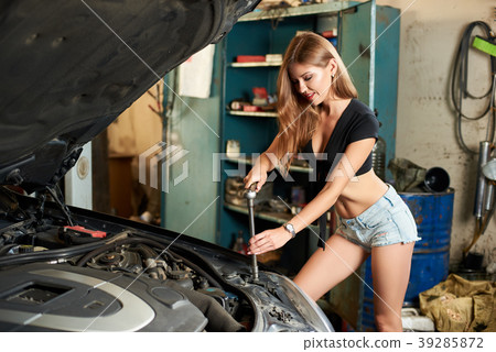 A girl poses while using wrench to tighten the bolts A girl poses while using wrench to tighten the bolts 39285872