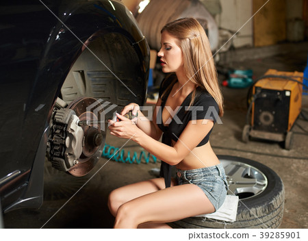 Woman focused on repairing steering mechanism of a black car Woman focused on repairing steering mechanism of a black car 39285901