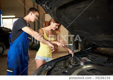 Mechanic shows a girl how to use a wrench to repair a car 39286156