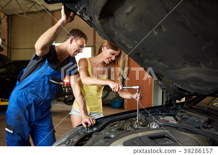 Young woman helps an auto mechanic repair car in garage 39286157