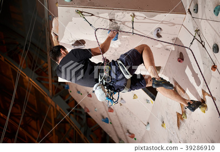 man practicing rock-climbing on rock wall indoors man practicing rock-climbing on rock wall indoors 39286910